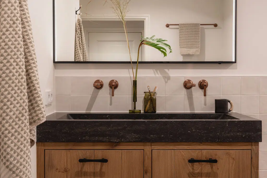 Impressie van een landelijke badkamer met witte wandtegels en Gessi kranen in geborsteld koper.