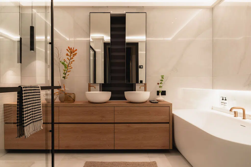 Impressie van een moderne badkamer met marmeren platen, ligbad, Gessi kranen en maatwerk houten badkamermeubel.