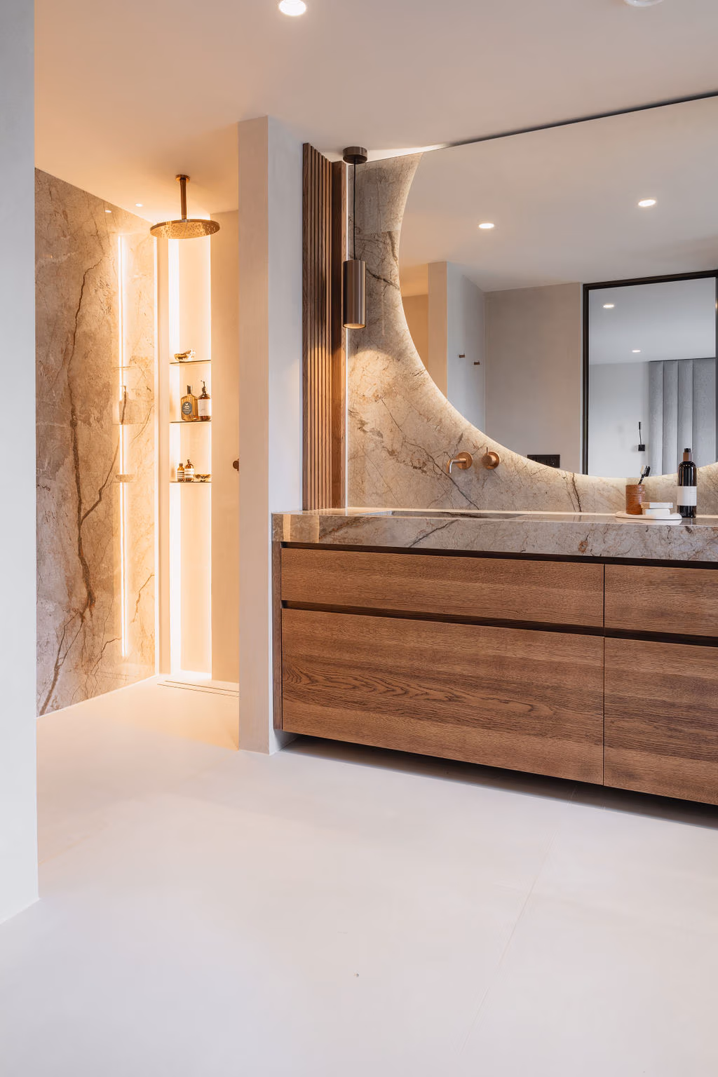 Luxe badkamer met inloopdouche, natuurstenen wanden, geïntegreerde verlichting, houten badkamermeubel en een grote spiegel met zachte backlight.